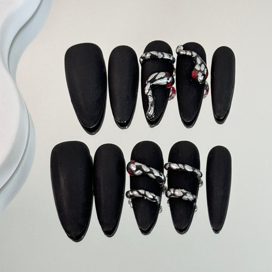 1. Sleek black chrome almondshaped presson nails with a frosted snake pattern for a chic look.