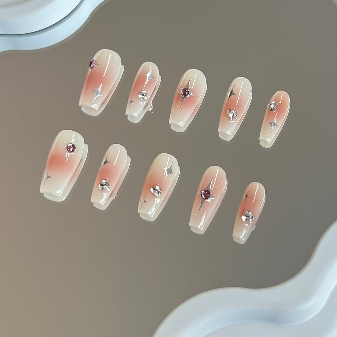 2. Handcrafted presson nails in a blush tone, featuring a medium coffin shape adorned with star motifs for a trendy touch.