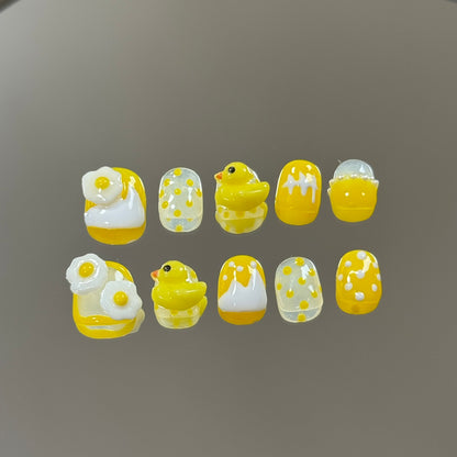 1. Short and round presson nails with vibrant yellow designs, perfect for a kidfriendly nail salon experience.