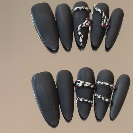 3. Elegant black chrome presson nails featuring an almond shape and a frosted snake design.