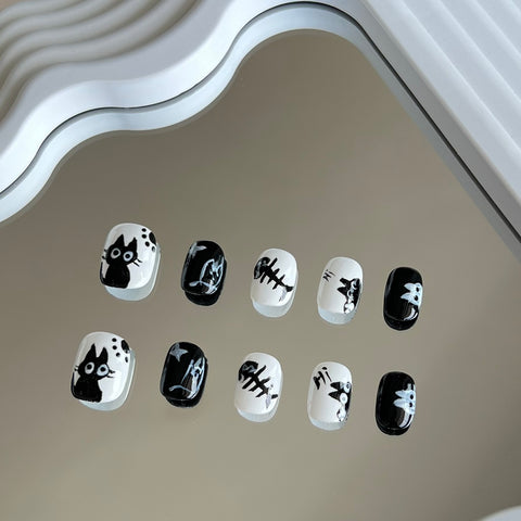 3. Elegant black and white nail art with cartoon cat eyes, tailored for short round nails, offering a unique presson nail experience.